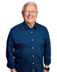 Senior man with grey hair wearing casual shirt and glasses with a happy and cool smile on face....