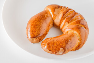 Tasty fresh crescent roll with golden crust, on light plate, selective focus.