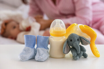 Breast pump with baby socks and toy on table in bedroom, closeup