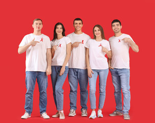 Fototapeta premium Group of young people with red ribbons on color background. World AIDS day concept