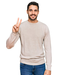 Naklejka premium Young hispanic man wearing casual clothes showing and pointing up with fingers number two while smiling confident and happy.