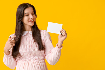 Pregnant woman with voting paper on yellow background