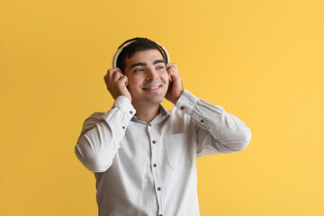 Happy young man in headphones on yellow background
