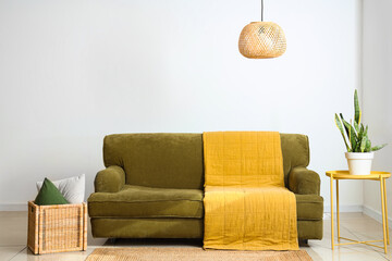 Interior of light living room with green sofa, table and basket