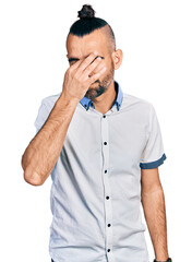 Hispanic man with ponytail wearing casual white shirt tired rubbing nose and eyes feeling fatigue and headache. stress and frustration concept.