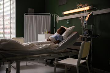 The young patient in the hospital ward lies on the bed, watching the outside world.