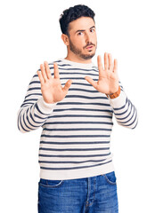 Young hispanic man wearing casual clothes moving away hands palms showing refusal and denial with...