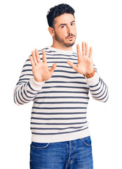 Young hispanic man wearing casual clothes moving away hands palms showing refusal and denial with afraid and disgusting expression. stop and forbidden.