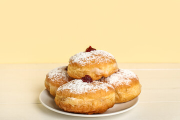 Plate with tasty donuts for Hanukkah celebration on light wooden table