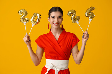 Beautiful young happy woman with figure 2024 made of balloons on yellow background. Chinese New...