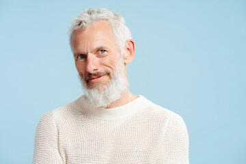 Portrait of handsome serious mature man wearing stylish sweater looking at camera isolated on...