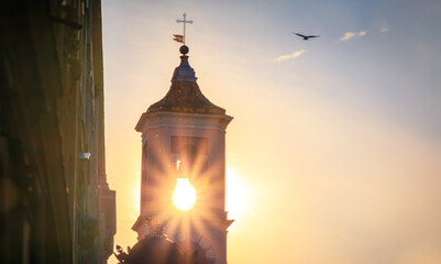 Sun burst behind The Caserne Rusca clock tower at sunset in the streets of the Old Town, Vieille...
