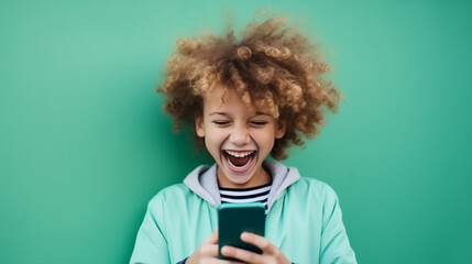 The little boy laughing as he looks at a mobile phone. Concept of starting soon with the mobile. - obrazy, fototapety, plakaty