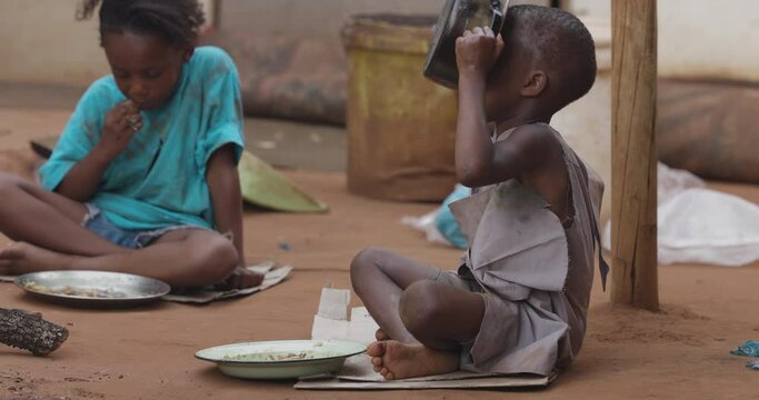 Poor, malnourished Black African child due to extreme poverty, drought and climate change. Drinking water from a cooking pot