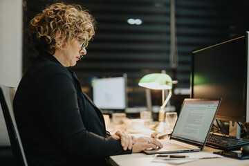 Lovely middle-aged businesswoman analyzing financial, sales, profit reports and teamwork results or...