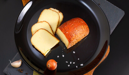 Circassian Adyghe sliced smoked cheese on a black background 