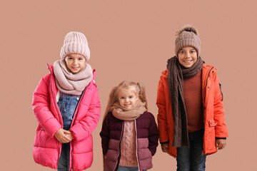 Cute children in winter clothes on beige background