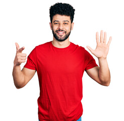 Naklejka premium Young arab man with beard wearing casual red t shirt showing and pointing up with fingers number seven while smiling confident and happy.