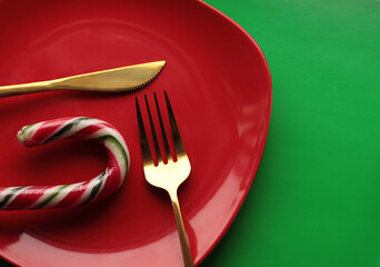 gold cutlery on a red plate on a green background red and green candy