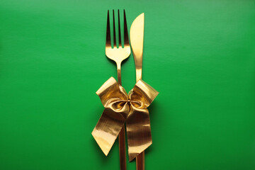 cutlery in gold color with a gold bow on a green background