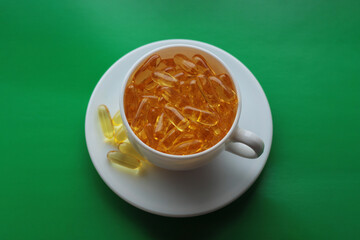 white cup and saucer filled with vitamins on green background
