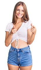 Fototapeta premium Young beautiful blonde woman wearing casual white tshirt pointing fingers to camera with happy and funny face. good energy and vibes.