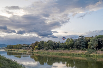 Fototapeta na wymiar Hot air balloon over Arno river on a cloudy day in Florence, Italy