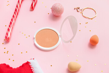 Powder with sponges, candy cane and Christmas decor on pink background
