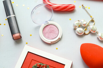 Christmas composition with makeup cosmetics, bracelet and confetti on white background