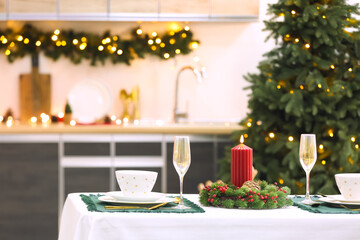 Table setting with Christmas wreath and candle in kitchen