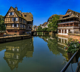 Fototapeta na wymiar Ornate traditional half timbered houses with blooming flowers along the canals in the picturesque Petite France district of Strasbourg, Alsace, France
