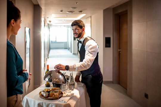 Male room service hotel staff waiter serving tray to hotel guest