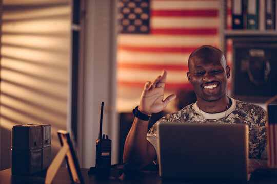 American soldier having a video call on his laptop while deployed in an army base