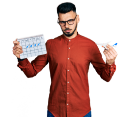 Young hispanic man with beard holding plane toy and travel calendar skeptic and nervous, frowning upset because of problem. negative person.