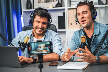 Host channel of creative broadcaster living by smartphone in positive podcast with special guest in list script to advice listeners, wearing headsets, using mic radio record at studio. Sellable.