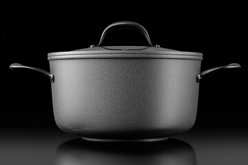 Stainless steel cooker with lid and chrome cookware on black background