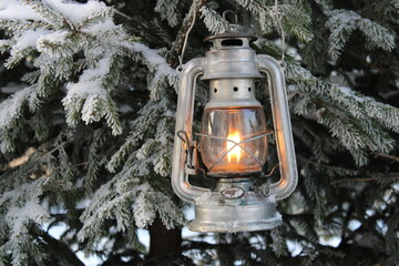 a winter kerosene lantern shines in the branches of a Christmas tree.