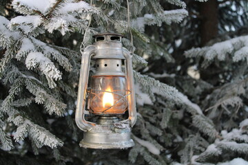 a winter kerosene lantern shines in the branches of a Christmas tree.