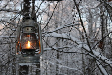 fantasy kerosene lantern shines near the evening winter forest.