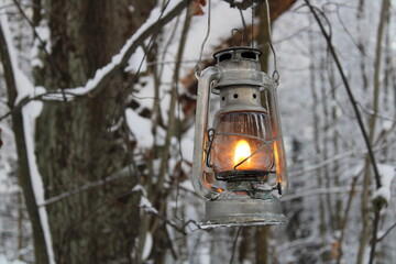fantasy kerosene lamp shines on a branch in the winter forest