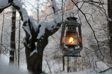 fantasy kerosene lamp shines on a branch in the winter forest