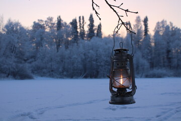 stock photo - a kerosene lantern shines in a snowy winter forest.