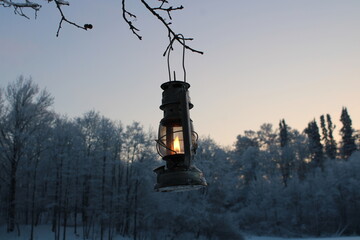 fantasy kerosene lantern shines near the evening winter forest.
