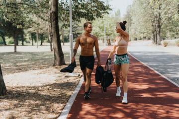 A fit Caucasian couple, after an active outdoor training session, walks home together with smiles and motivation. Their strong muscles reflect their dedication to fitness.