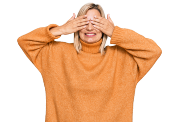 Middle age caucasian woman wearing casual winter sweater covering eyes with hands smiling cheerful and funny. blind concept.