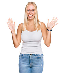 Young blonde girl wearing casual style with sleeveless shirt showing and pointing up with fingers number ten while smiling confident and happy.