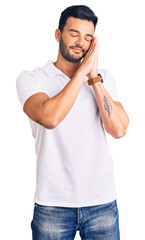 Young handsome hispanic man wearing casual clothes sleeping tired dreaming and posing with hands together while smiling with closed eyes.