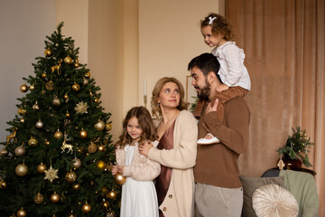 happy family parents and daughters enjoying their time together at home near Christmas tree