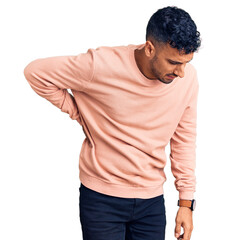 Young hispanic man wearing casual clothes suffering of backache, touching back with hand, muscular pain