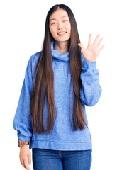 Young beautiful chinese woman wearing casual turtleneck sweater showing and pointing up with fingers number five while smiling confident and happy.